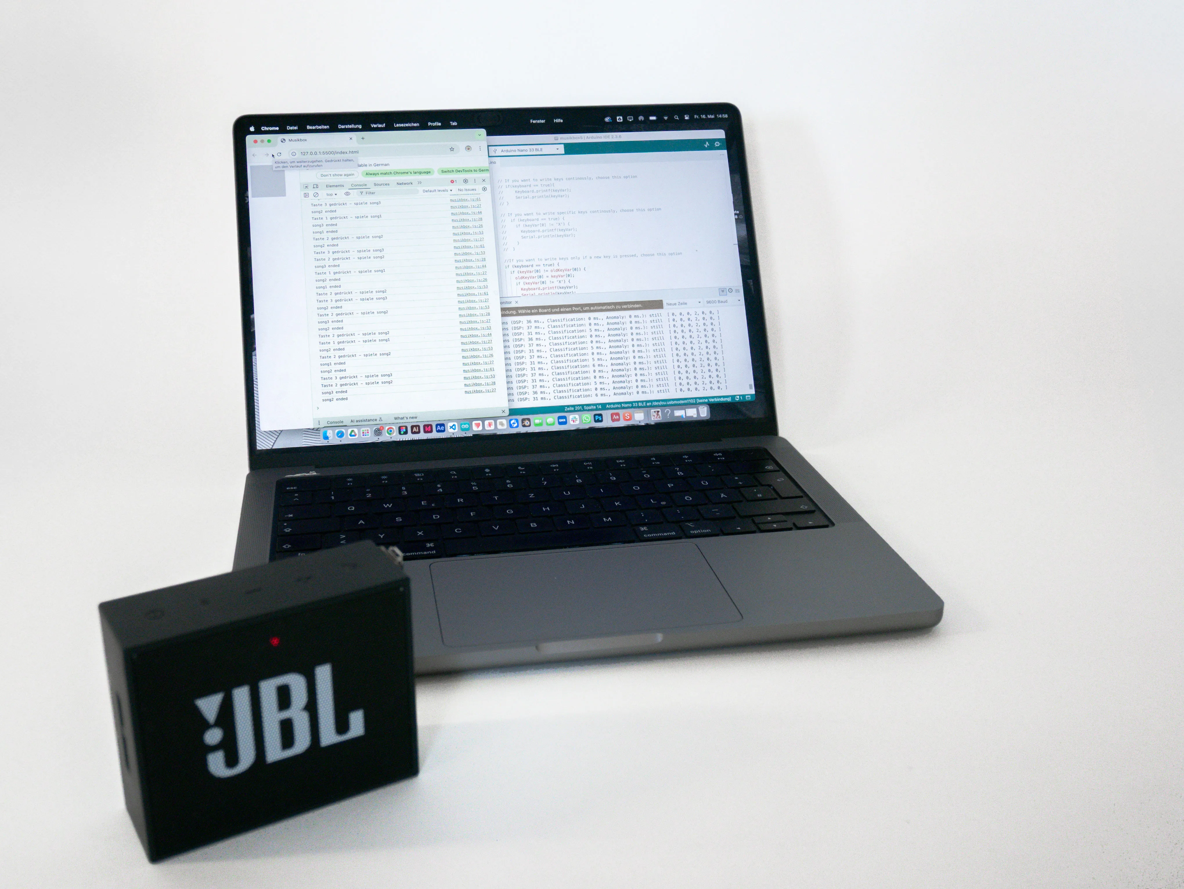 DanceBox prototype: Laptop displays development environment with code and data streams for motion recognition. A speaker sits connected nearby, serving as the audio output device for the AI-powered dance collaboration system.