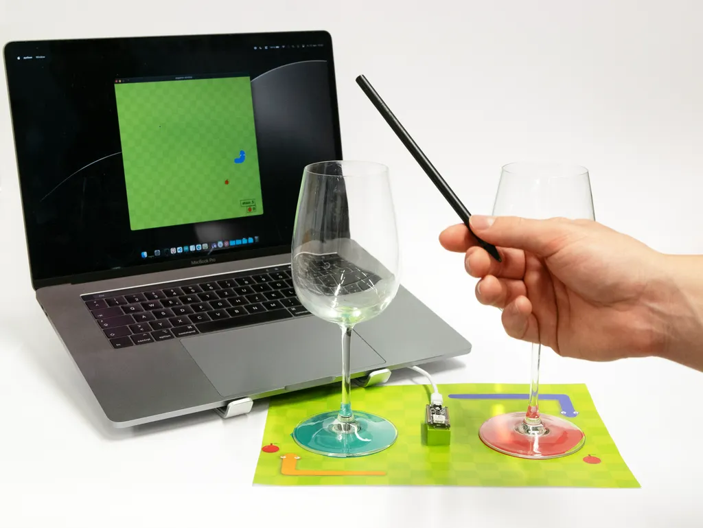 The image shows the game Snake being played on a computer with sound input by tapping two different glasses.